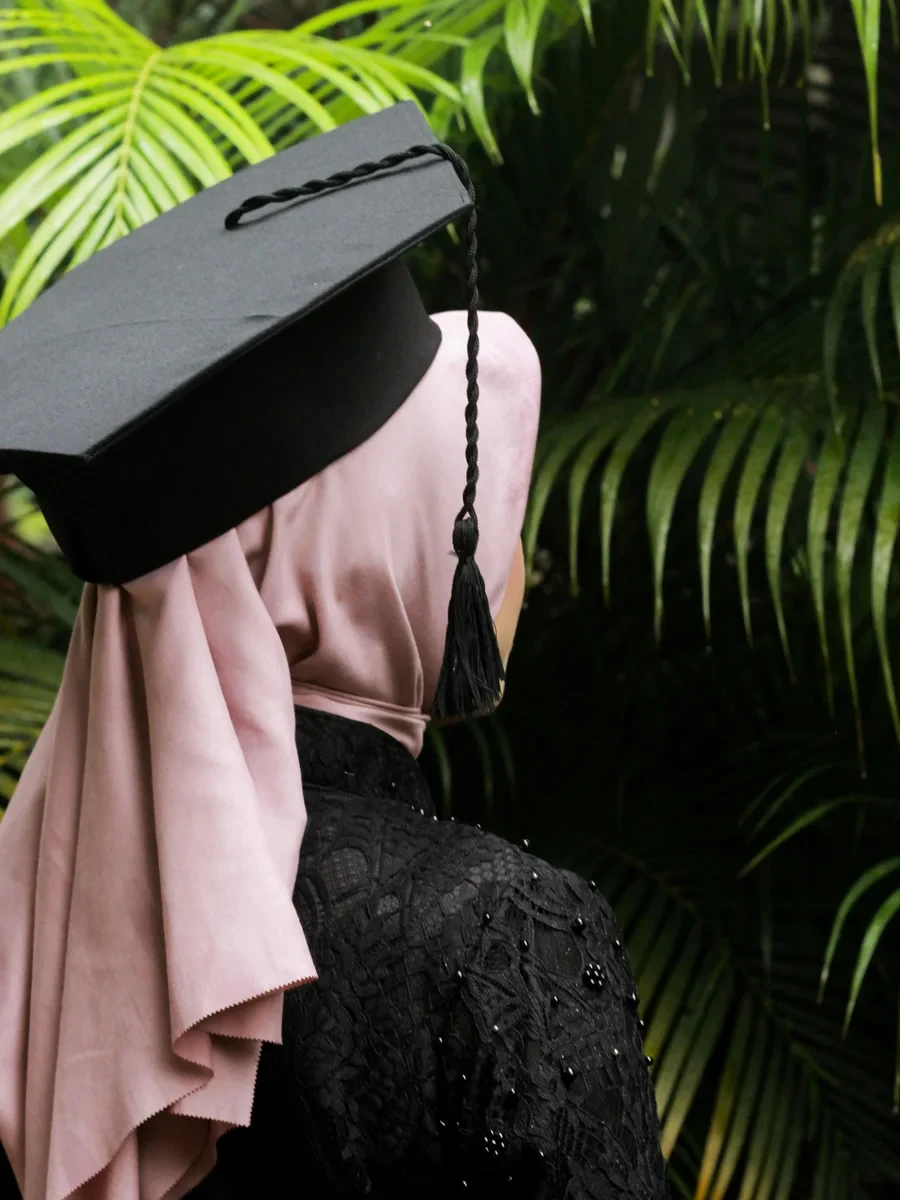 A young Muslim woman in a graduation cap, seen from behind