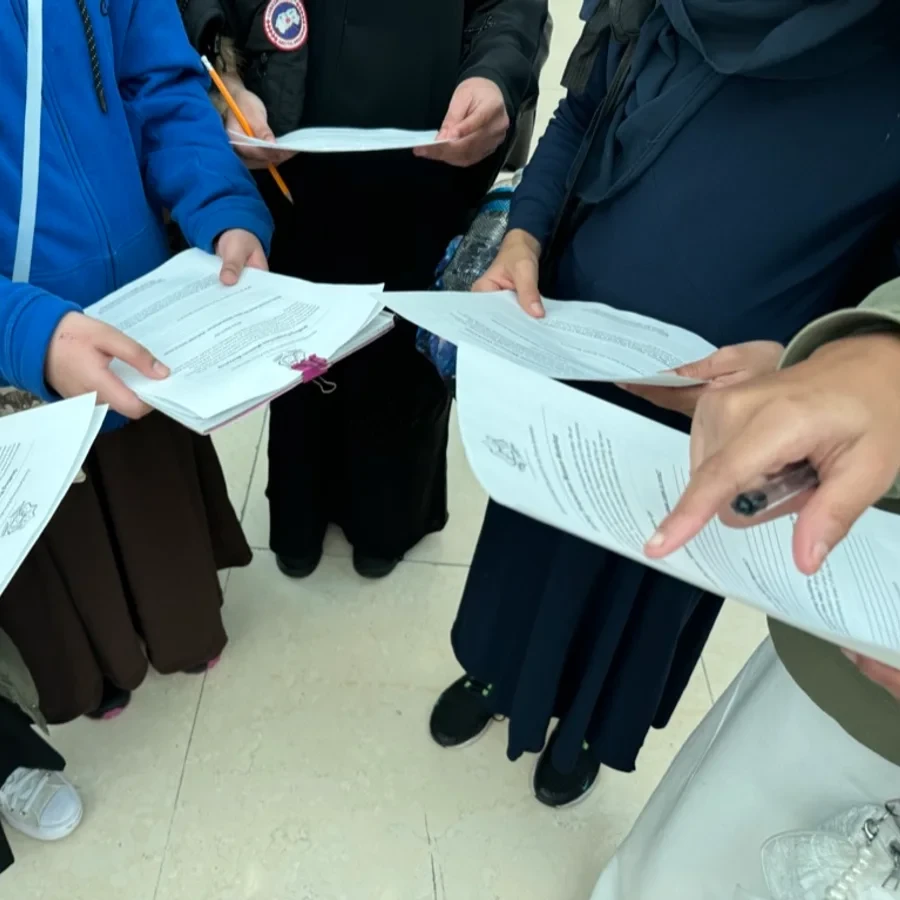Students being handed printed work during a session