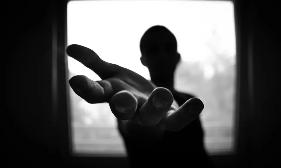 A hand reaching out towards the camera from the shadows