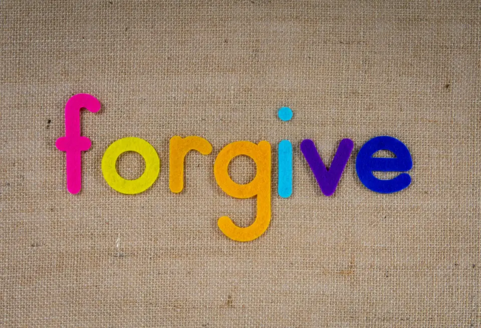 The word forgive spelled out in colourful letters on hessian